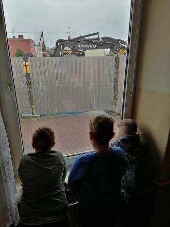Chłopcy z okna klasy przyglądaja się pracy koparki